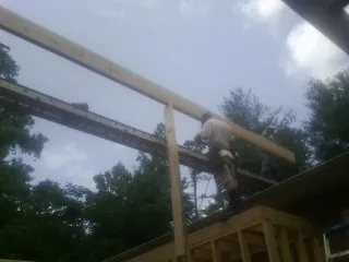 Carpenter setting a ridge beam over a new addition frame — Ice Dam Removal by Roofing Brothers in Alma